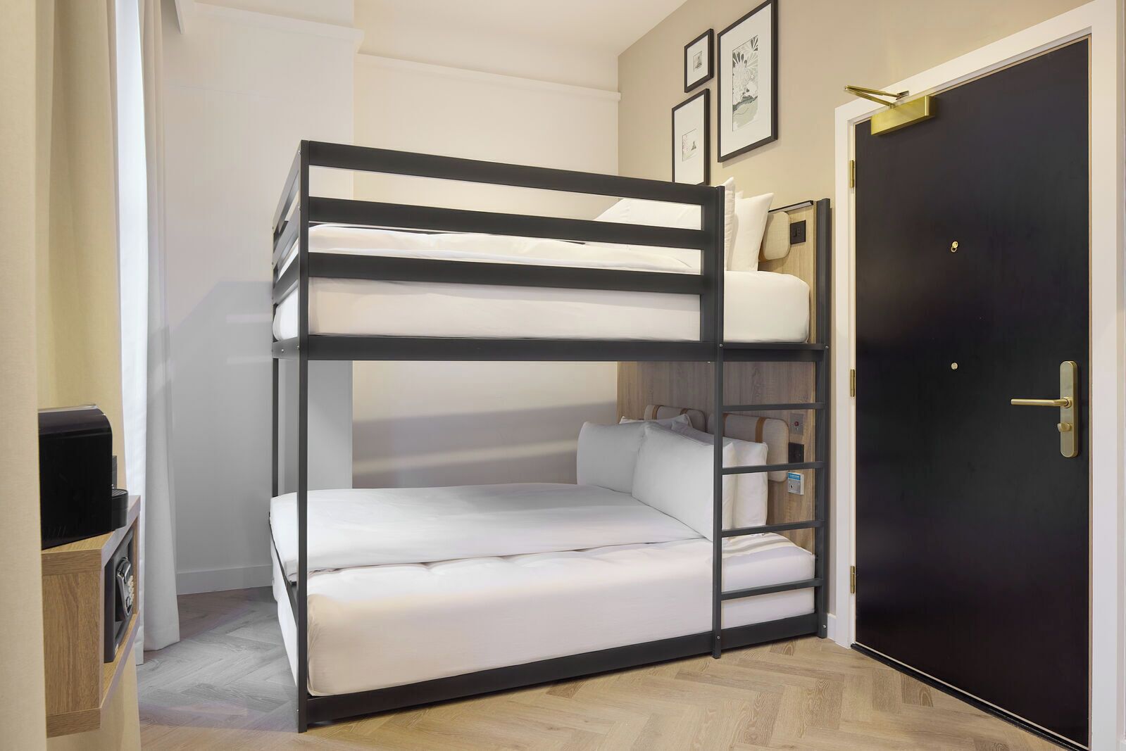 Ein Stockbett mit Schreibtisch und Stuhl, eine schwarze Tür und ein kleines Regal mit Büchern.