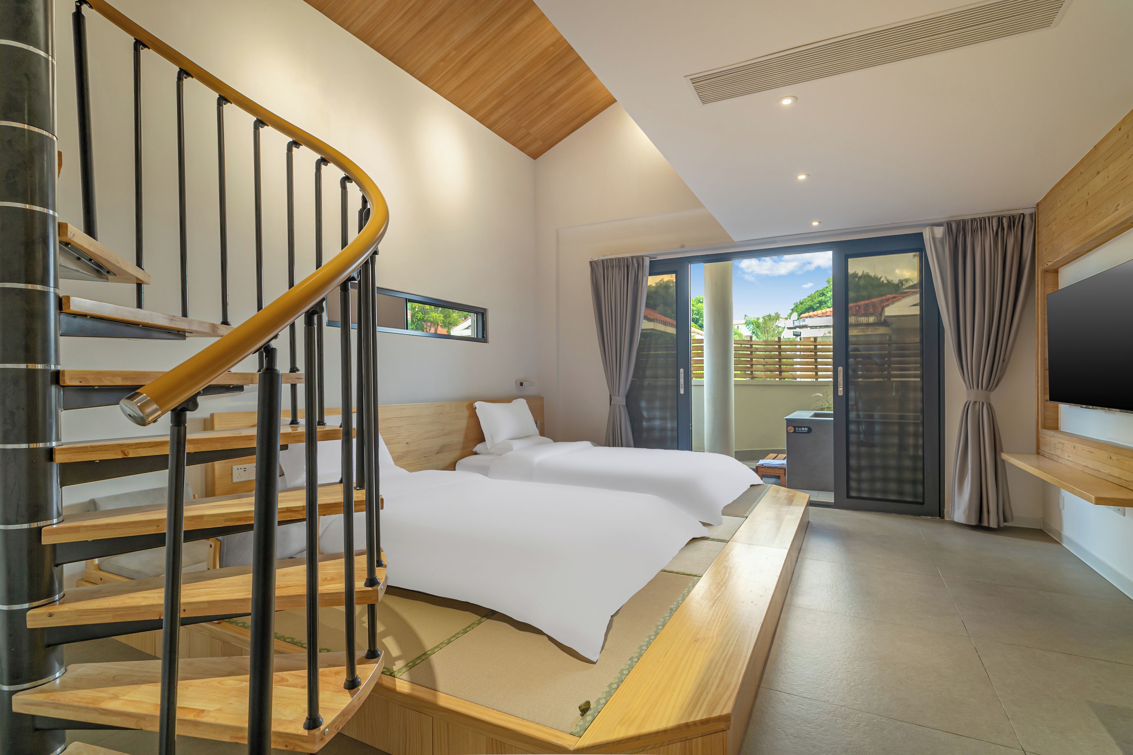 A modern hotel room with a wooden staircase, a bed with white bedding, a large window with curtains, and a flat-screen TV mounted on the wall.