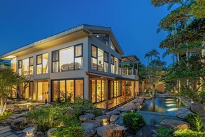 Una casa moderna de dos pisos con ventanas amplias, piscina y un jardín bien cuidado.