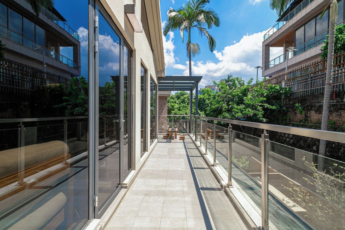 A modern building with large glass windows, a covered walkway, and outdoor seating.