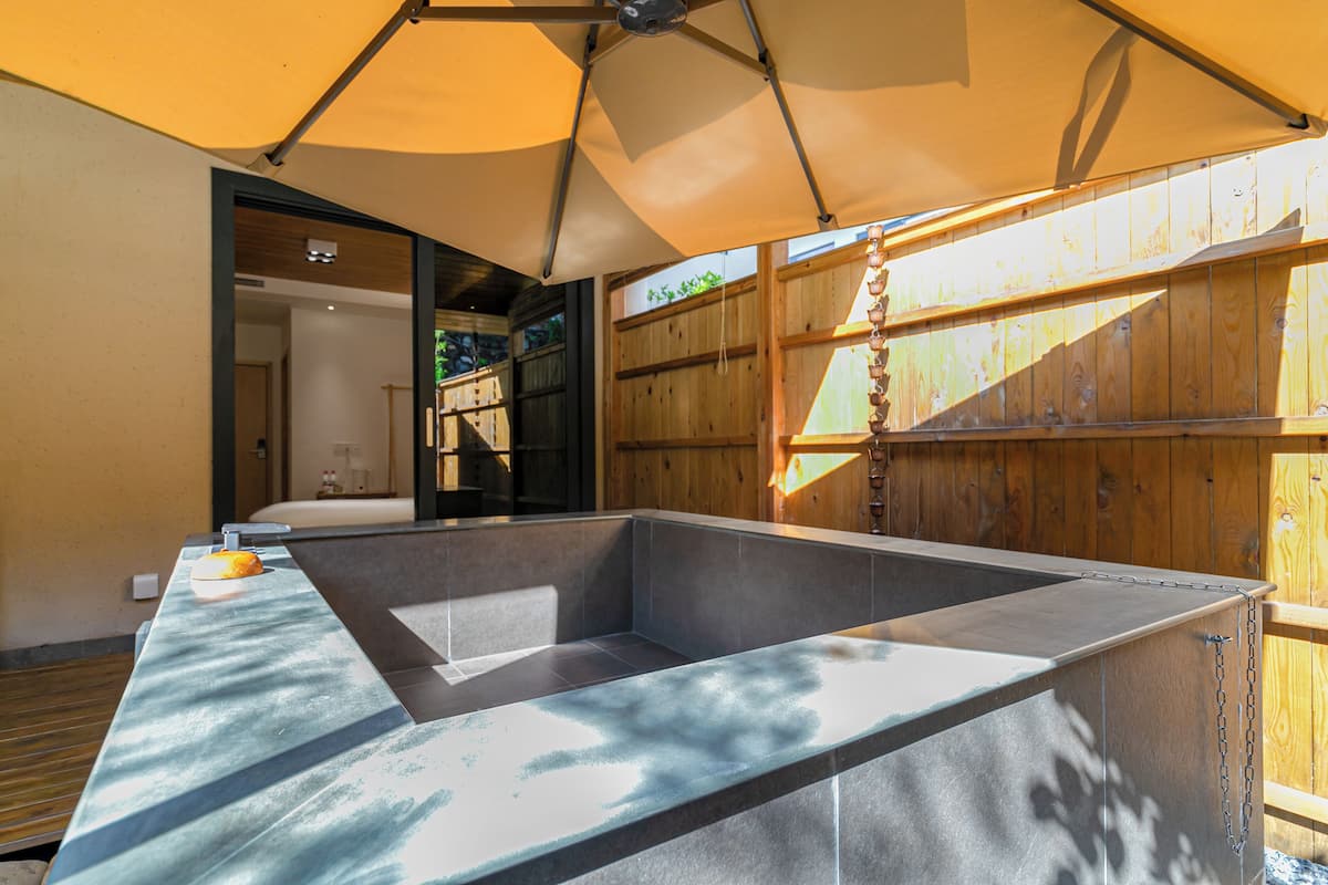 A modern kitchen with a large island, wooden accents, and a view of the outdoors.