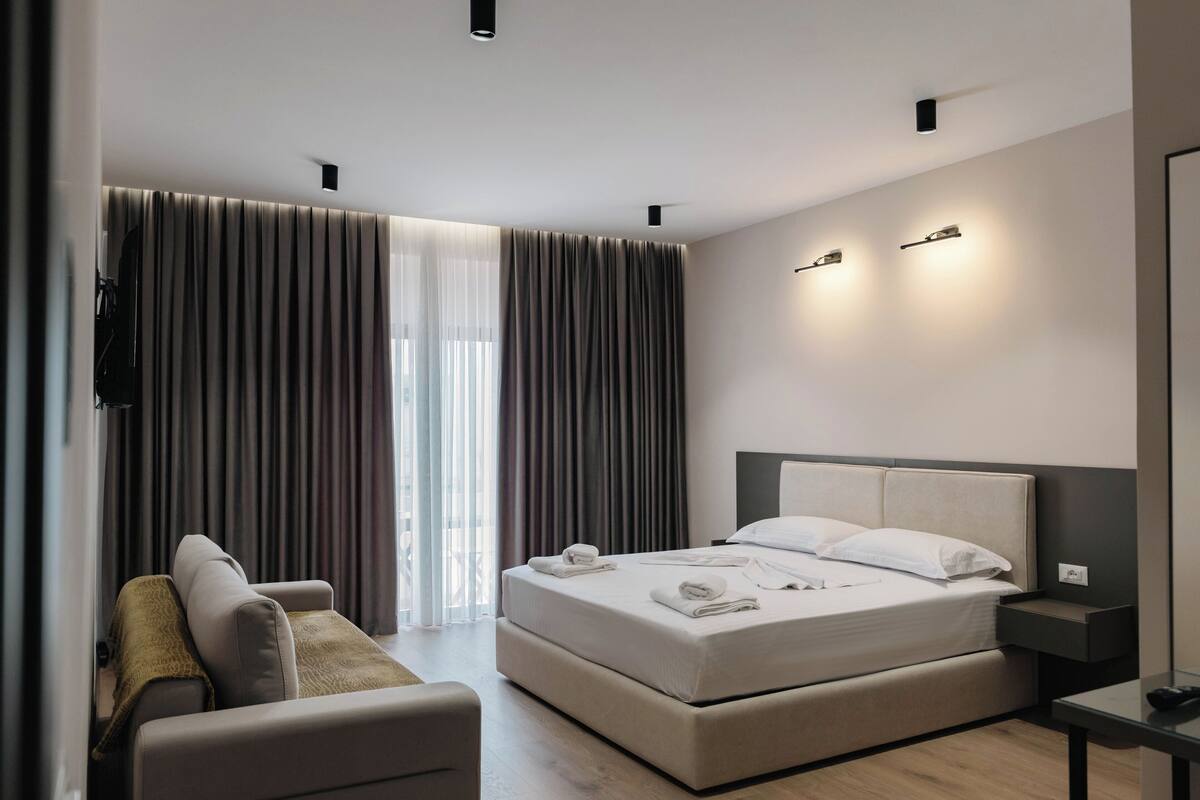 Una habitación de hotel moderna con una cama grande, un sofá y un televisor.