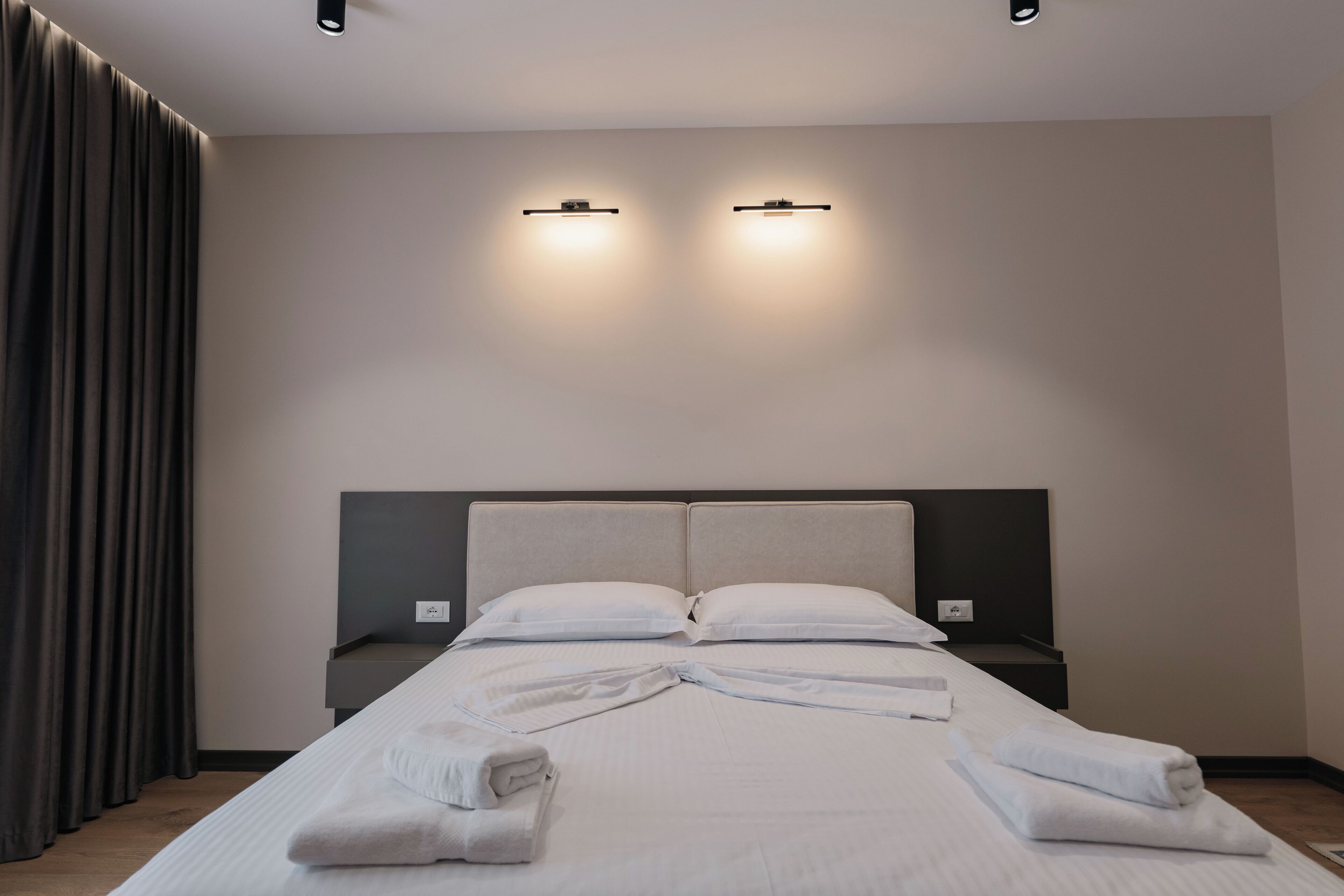 Une chambre d’hôtel moderne avec un grand lit, deux tables de chevet et une tête de lit.