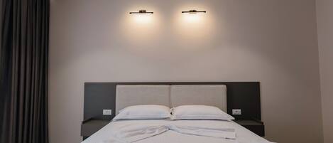 Une chambre d’hôtel moderne avec un grand lit, deux tables de chevet et une tête de lit.