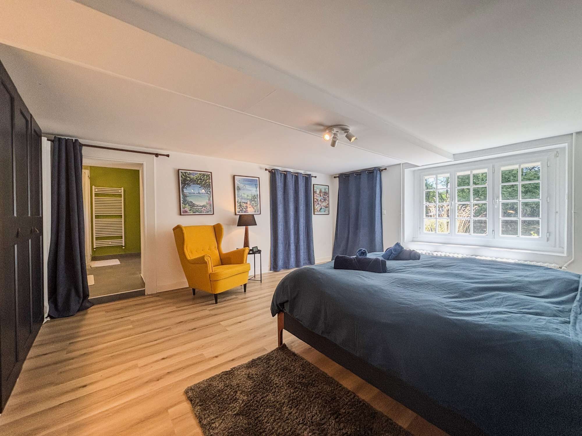 A bedroom with a bed, a chair, a window, and a door.