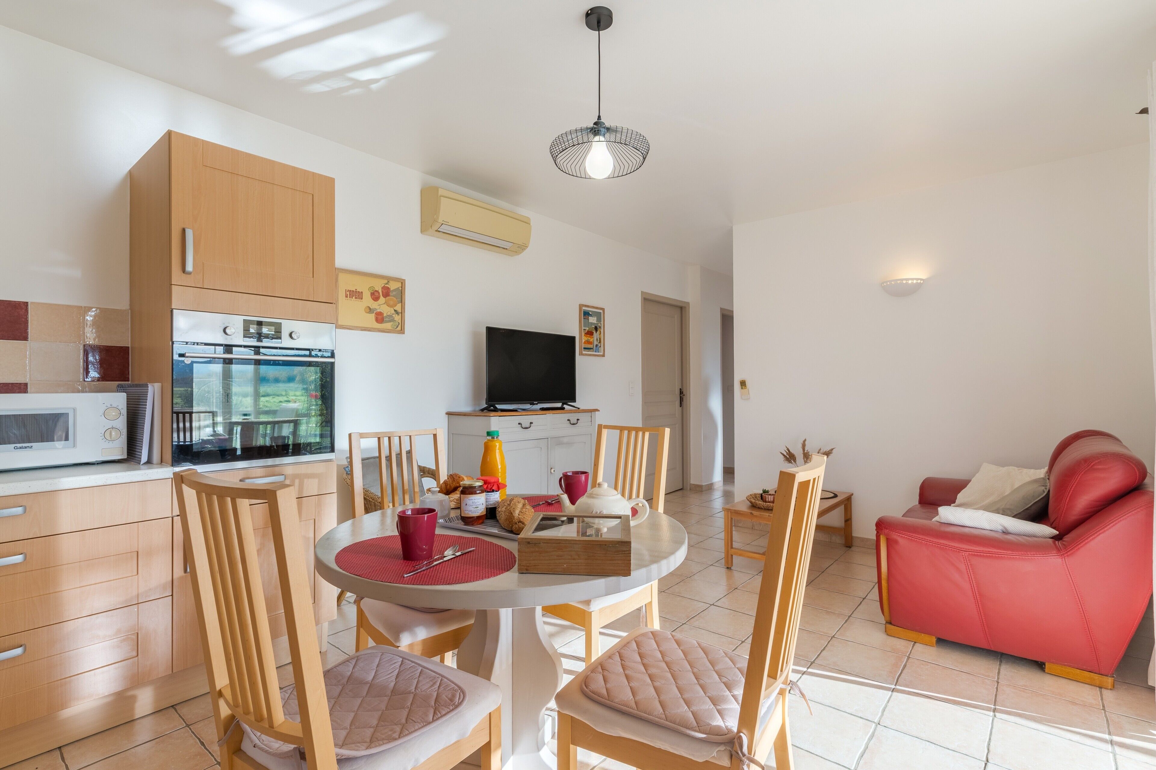 A modern kitchen with a microwave, oven, and dining area with chairs and a table.