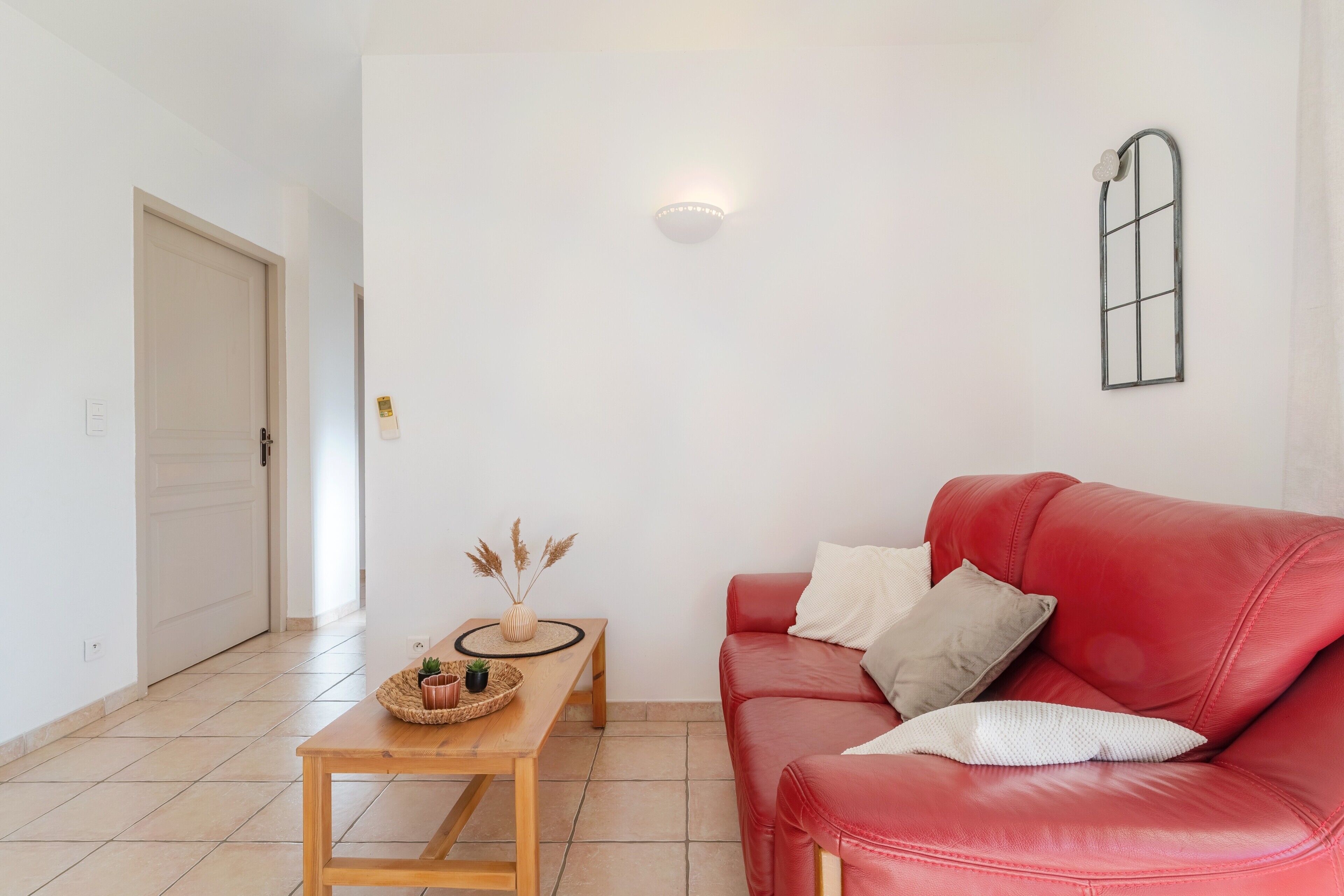 A living room with a red leather sofa, a wooden coffee table, and a wall-mounted light fixture.