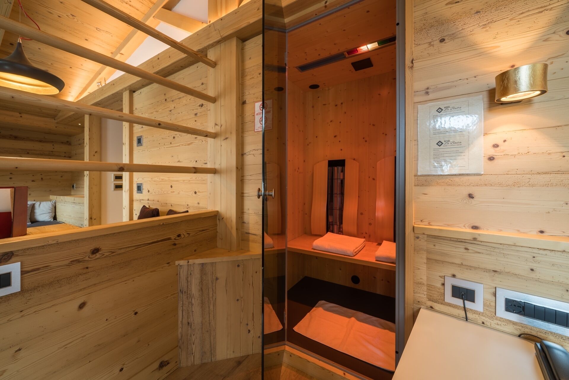 Une cabane en bois équipée d’un sauna, d’un lit et d’une petite table avec une lampe.