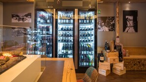 A wine cellar with multiple refrigerated wine racks, wooden crates, and a wooden table with a decorative centerpiece. - Hotel La Baita (Madonna di Campiglio)