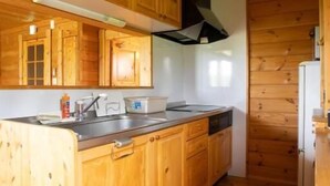 A wooden-paneled kitchen with a central island, wooden cabinets, and a stainless steel sink.