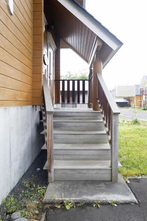 A wooden staircase leading to a porch with a metal railing.