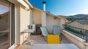 A balcony with a table, chairs, and a view of the surrounding landscape. - Gîte 'Fleur De Thym' with Shared Pool, Communal Terrace and Air Conditioning (Gréoux-les-Bains)
