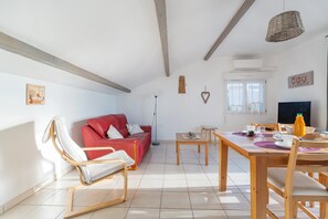 Uma sala de estar moderna com um sofá vermelho, mesa de jantar de madeira e uma televisão.