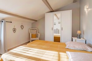 Quarto com cama, guarda-roupa, cadeira, mesa de cabeceira e decoração nas paredes.