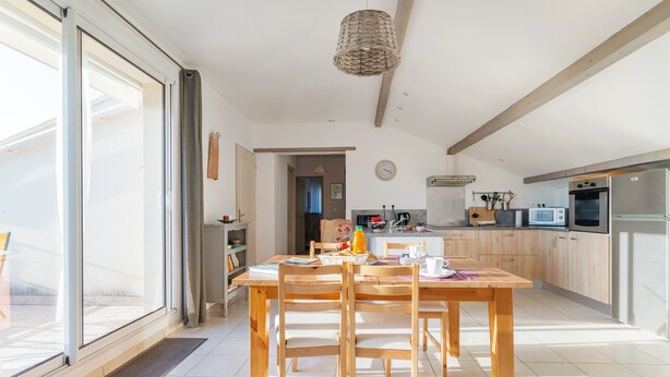 A modern kitchen with wooden cabinets, a dining table, and a large window. - Gîte 'Fleur De Thym' with Shared Pool, Communal Terrace and Air Conditioning (Gréoux-les-Bains)