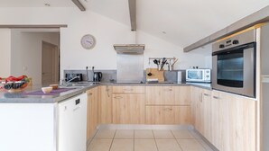 A modern kitchen with wooden cabinets, a dishwasher, a microwave, and an oven. - Gîte 'Fleur De Thym' with Shared Pool, Communal Terrace and Air Conditioning (Gréoux-les-Bains)