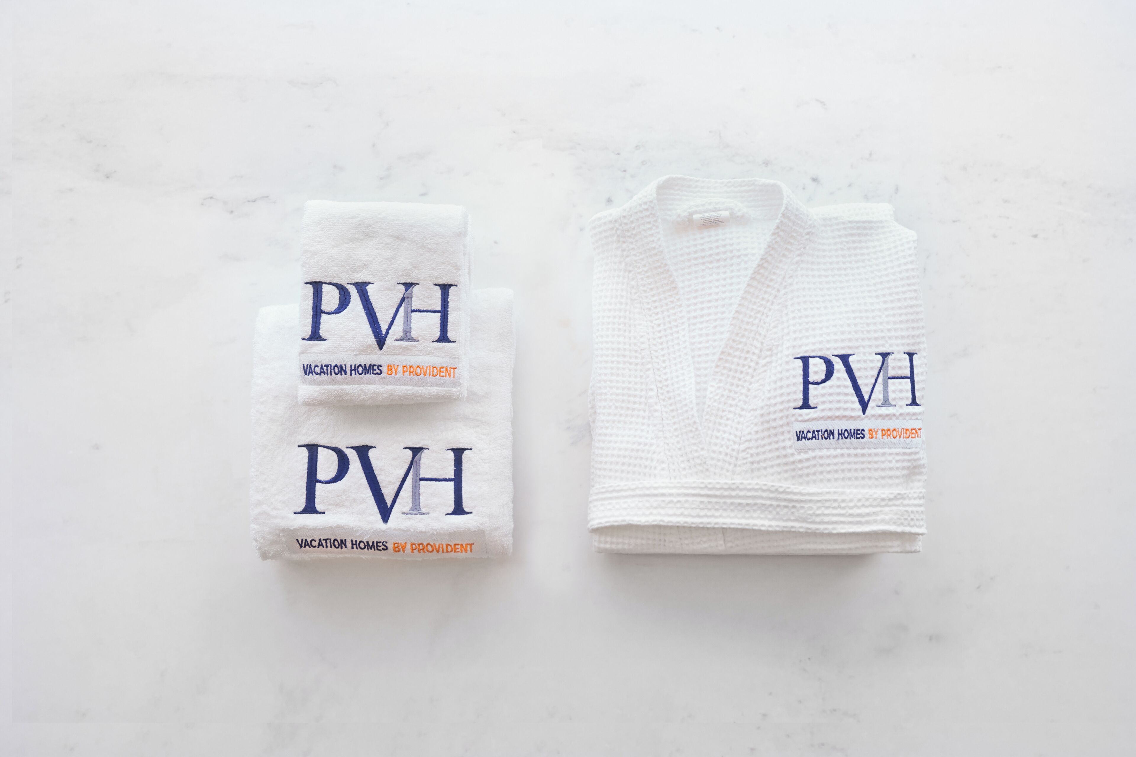 Two white towels with the text "PVH Vacation Homes by Provident" on them.