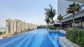 A swimming pool with a view of high-rise buildings and palm trees. - PVH - Inviting Studio - Palm Tower (Dubai)