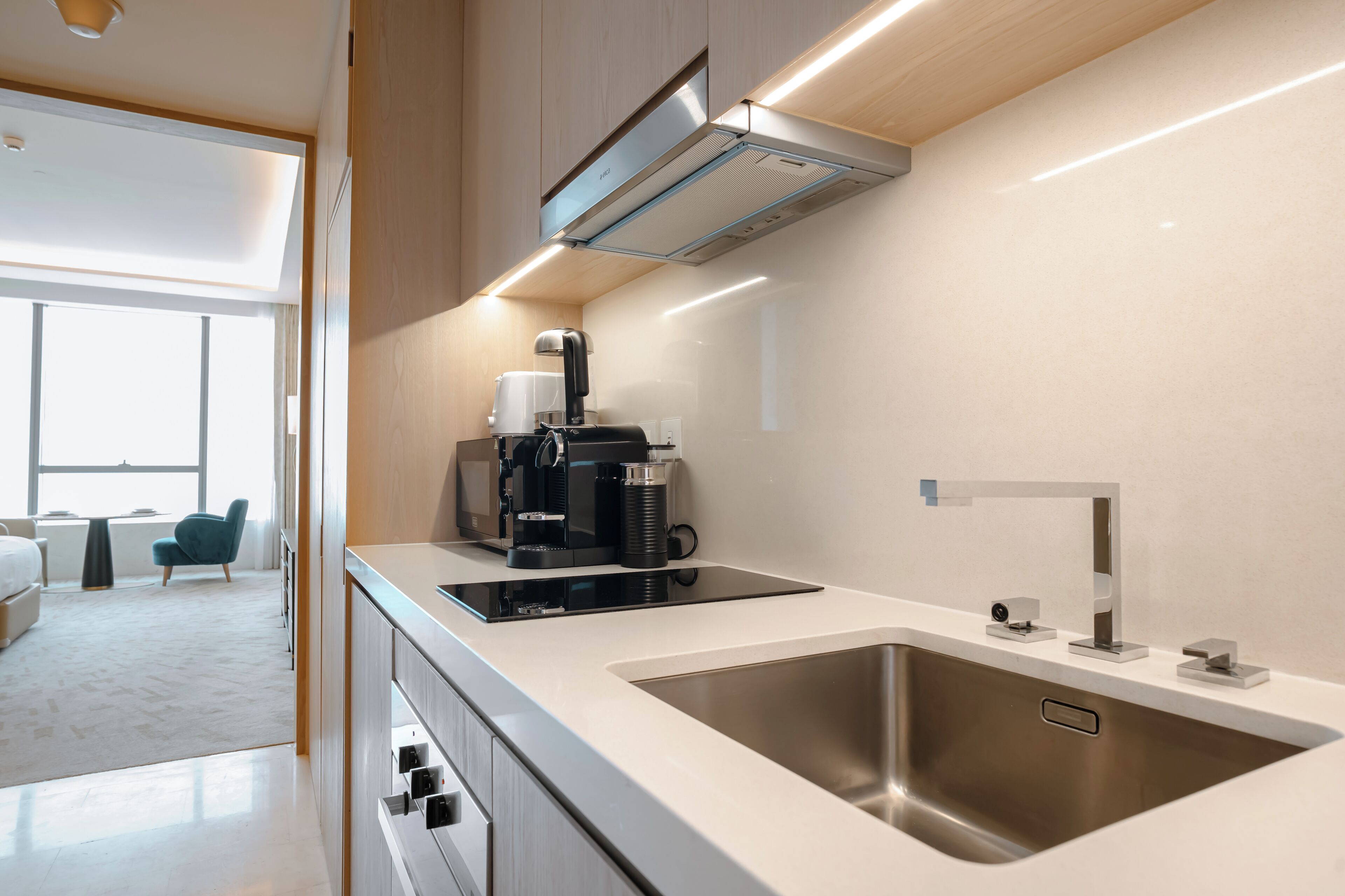 A modern kitchen with a stainless steel sink, a coffee maker, and a built-in range hood.