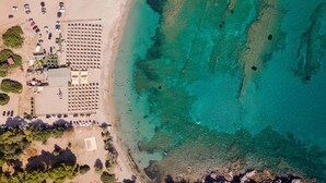 An aerial view of a coastal area with a parking lot, beach, and clear turquoise waters. - Villa Nefeli Athenian Riviera (Saronikos)