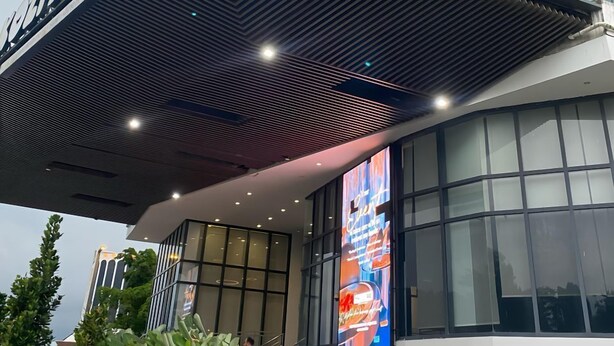 Een modern gebouw met een glazen gevel en een bord waarop “LOBBY DROP OFF” staat.