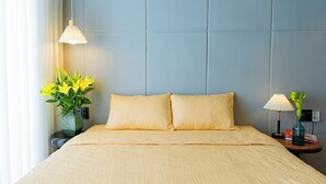 A hotel room with a large bed, a nightstand with a lamp, and a vase with flowers. - Charming Private Room with Balcony – Local Homestay with Host Family, Cozy Stay (Tỉnh Thừa Thiên Huế)