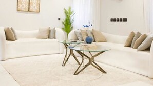 Un salon moderne avec un canapé blanc, une table basse en verre et des objets décoratifs.