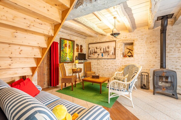 Une pièce chaleureuse avec un canapé, des fauteuils, une table, un tableau, une cheminée et un plafond en bois.