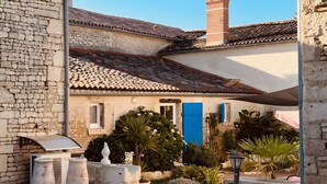 A courtyard with a stone wall, a blue door, and potted plants. - Guest Room 'Chez Jacques - Zen' with Private Terrace, Wi-Fi and Air Conditioning (Saint-Martin-de-Fraigneau)
