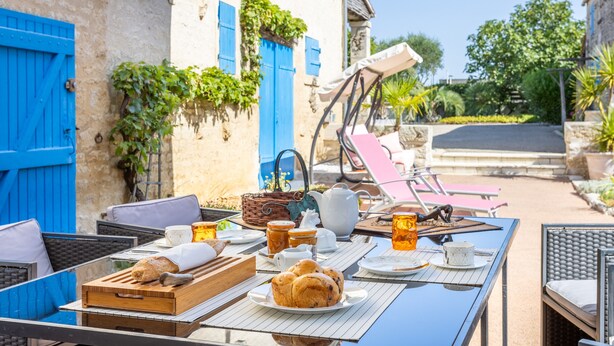 An outdoor dining area with a table set for breakfast, including bread, pastries, and beverages. - Guest Room 'Chez Jacques - Zen' with Private Terrace, Wi-Fi and Air Conditioning (Saint-Martin-de-Fraigneau)