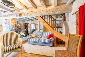 Un interior rústico con una escalera de madera, un sofá a rayas y una silla de mimbre.