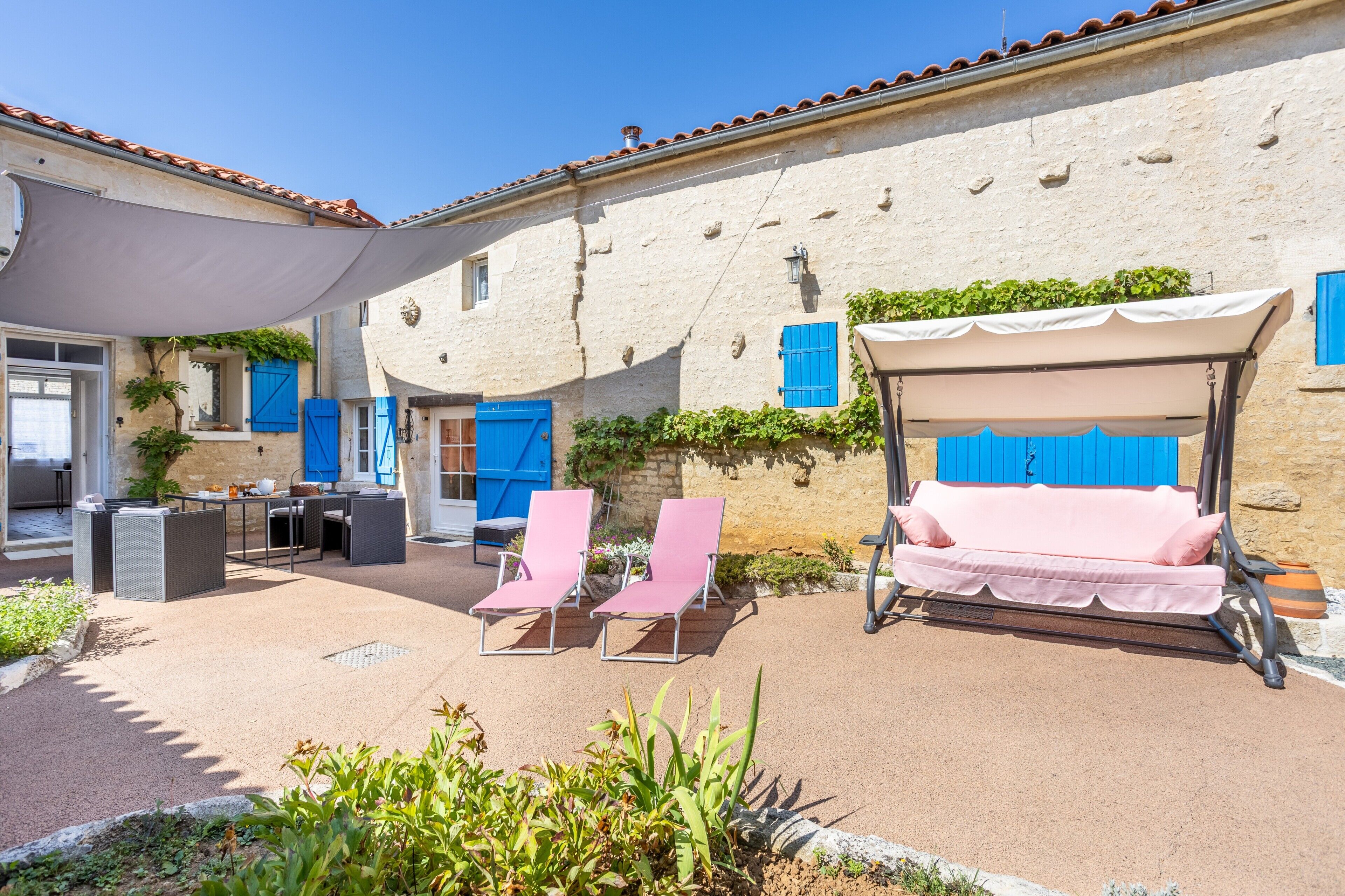 An outdoor seating area with a table, chairs, and a covered sofa.
