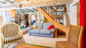 A rustic interior with a wooden staircase, a striped sofa, and a wicker chair.