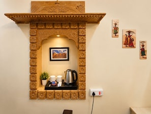 Una habitación con chimenea de piedra decorativa, un cuadro enmarcado encima y una bandeja con cafetera y tazas.