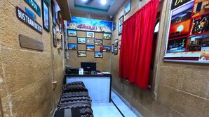 Un couloir étroit avec un comptoir d’accueil, un banc et un mur décoré de tableaux et de panneaux indiquant des informations sur les visites guidées.