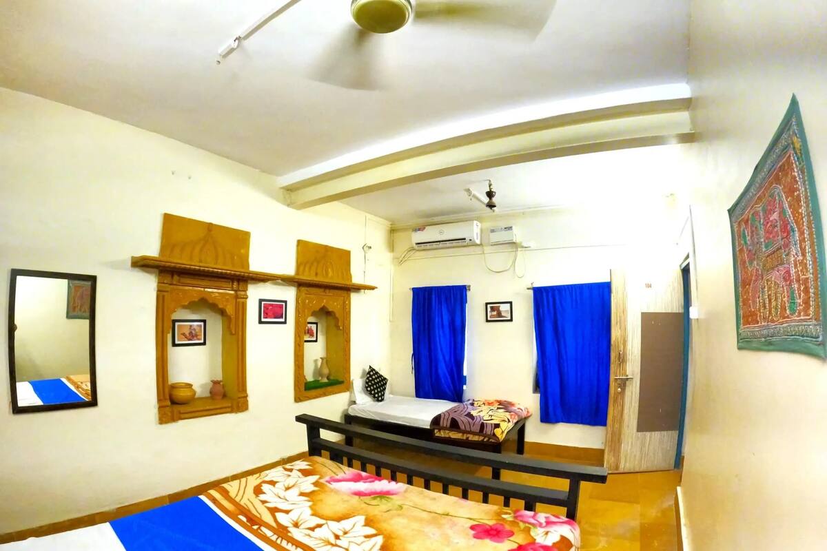 A bedroom with a bed, a mirror, a wardrobe, and a ceiling fan.