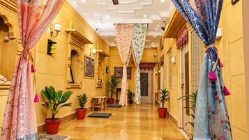 A hotel corridor with a ceiling fan, potted plants, and traditional decor.