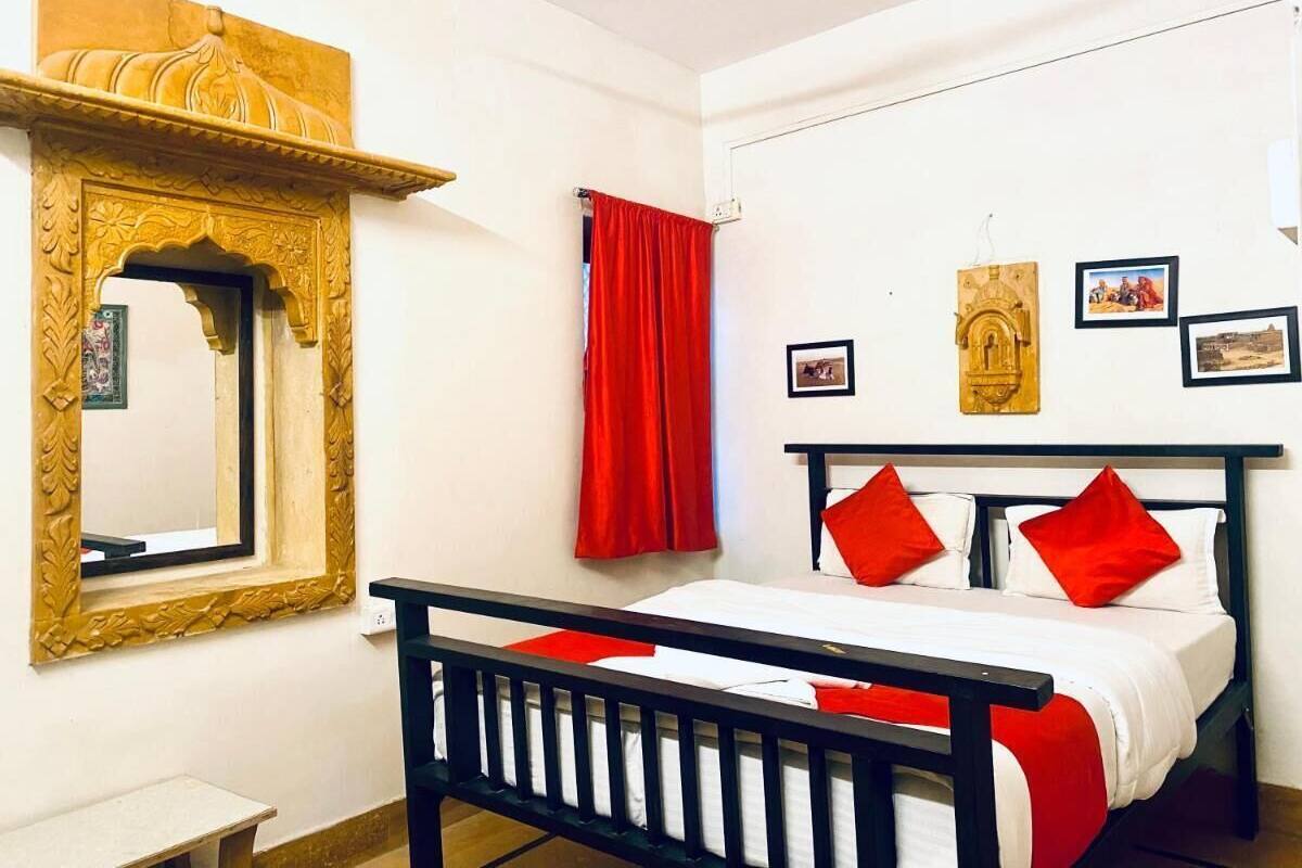 A bedroom with a bed, a wooden headboard, a red curtain, a mirror with a decorative frame, and wall-mounted pictures.