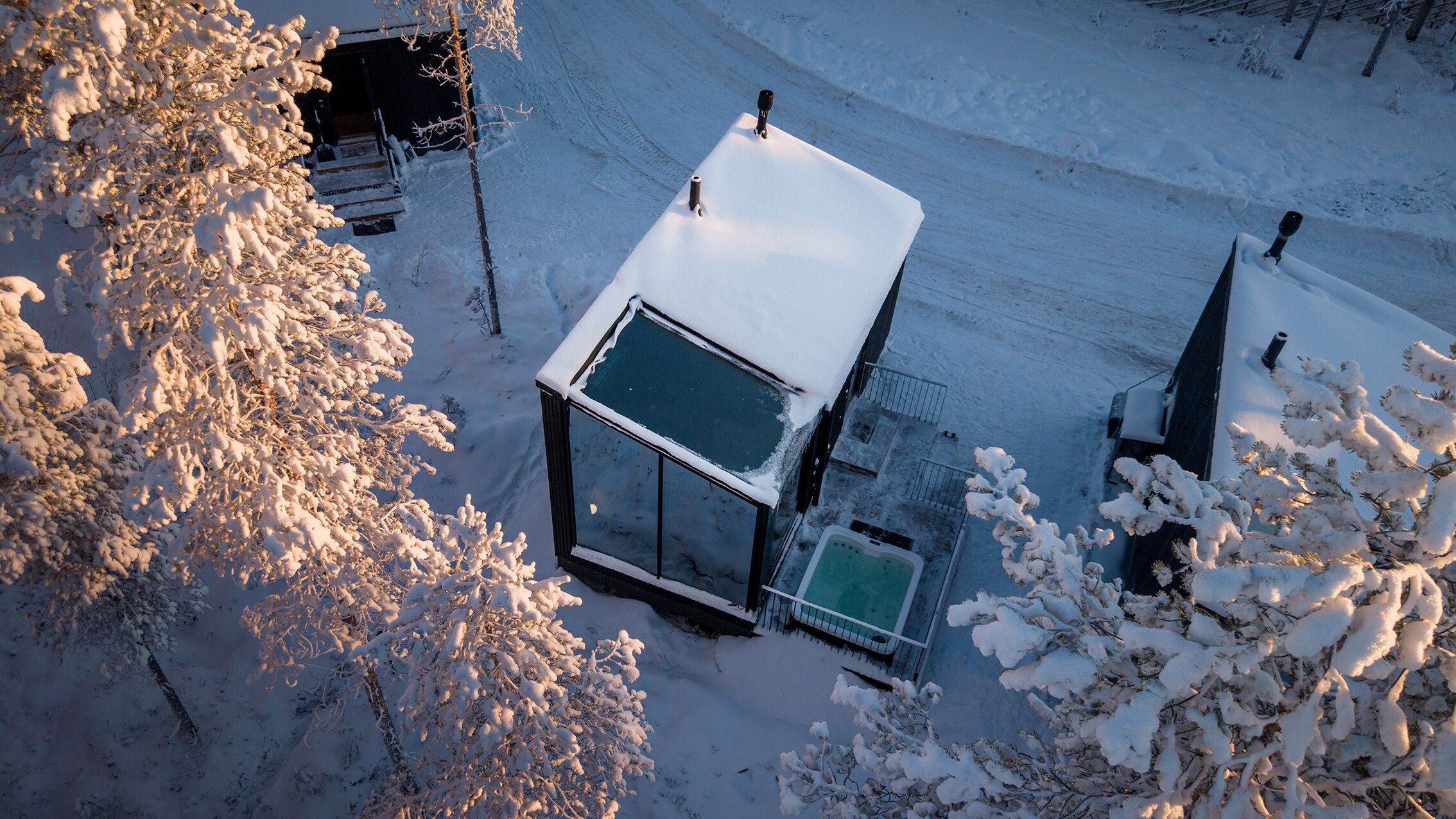 Una casa cubierta de nieve con un invernadero, una pequeña terraza y un patio nevado.