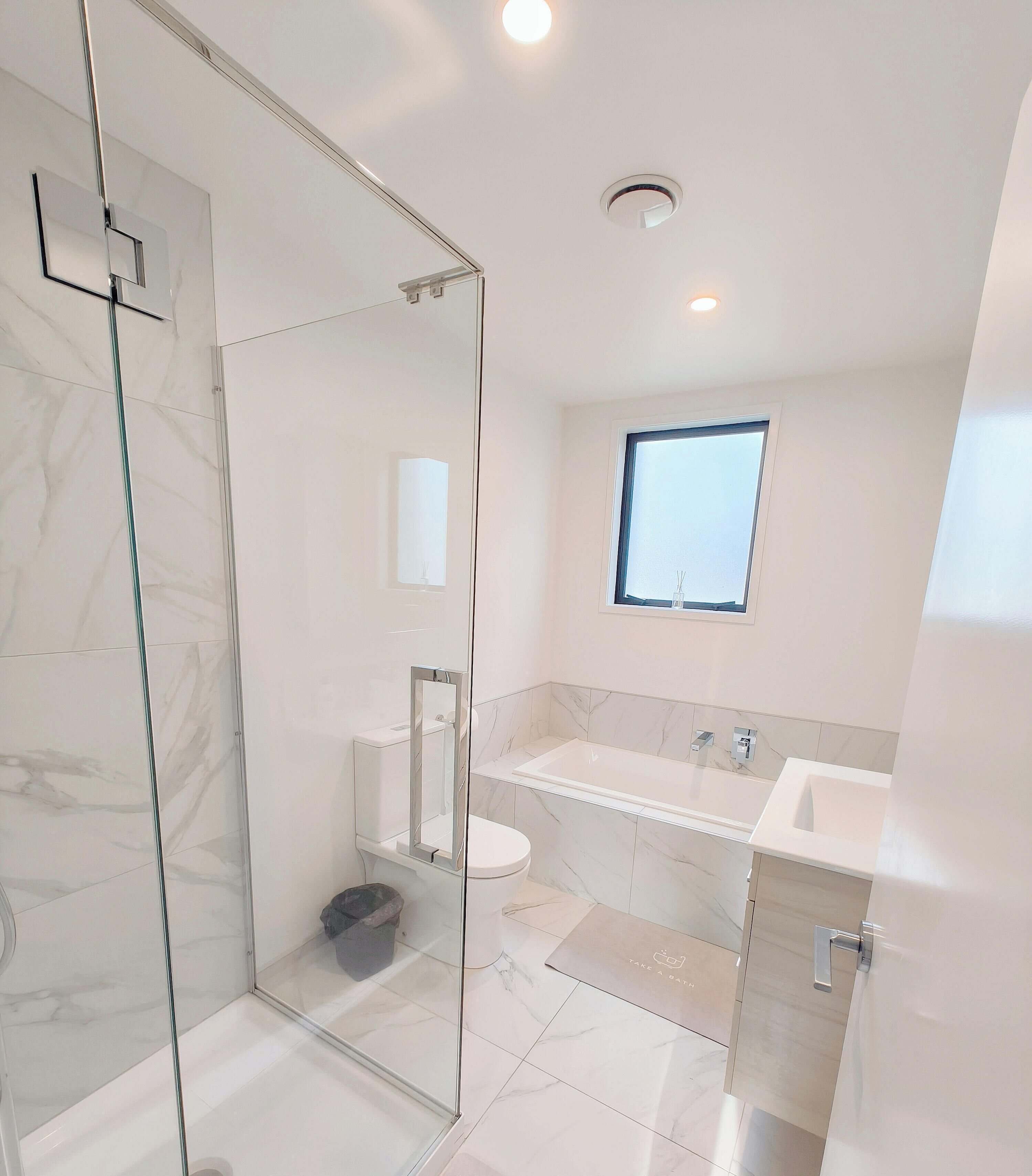 A modern bathroom with a glass shower enclosure, a toilet, a sink, and a bathtub.