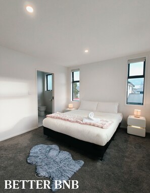 A modern bedroom with a large bed, bedside tables, a window, and a view of the outside. - Modern & New • 3 Beds • 6 Guests (Upper Hutt)