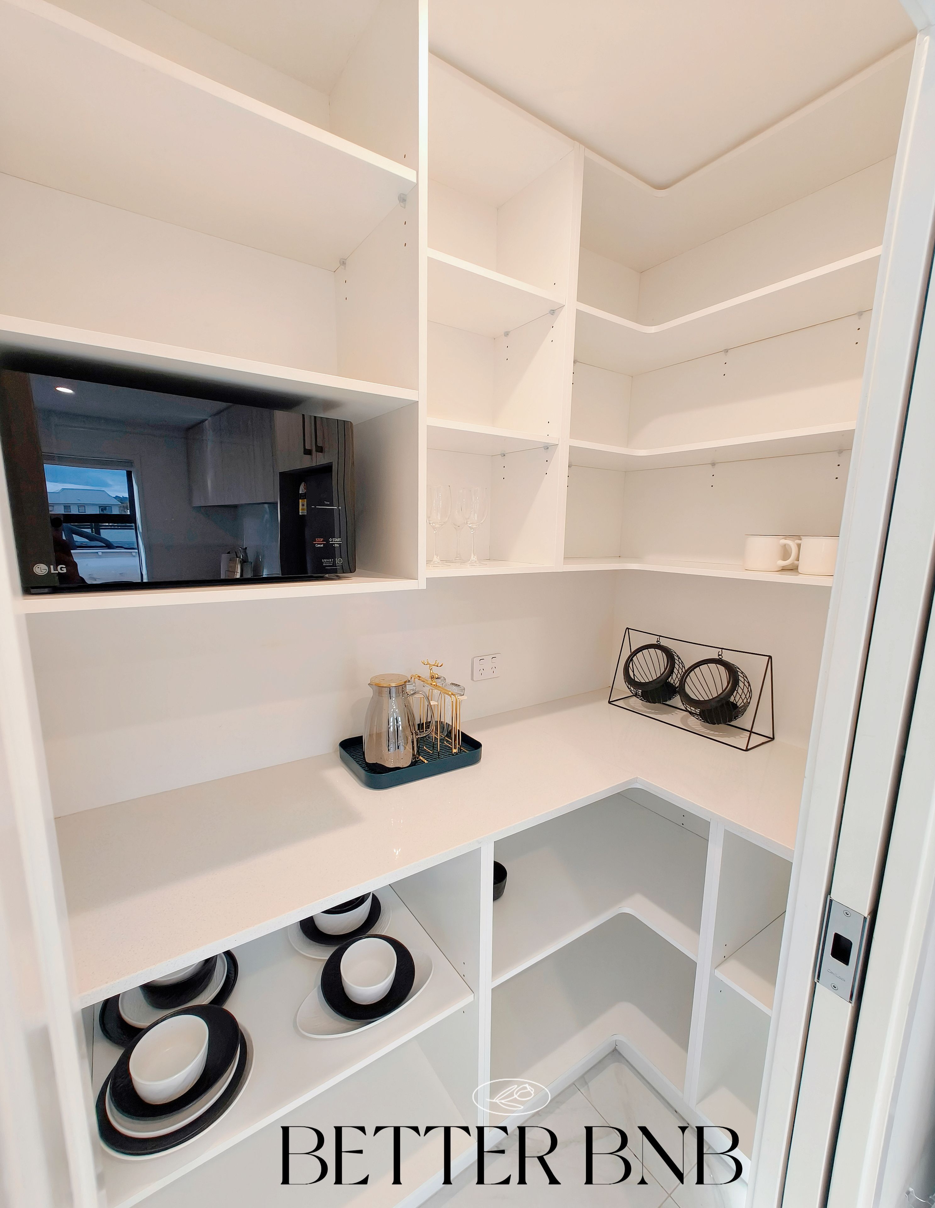 A modern kitchen with white cabinetry, a black coffee maker, and a wine rack.