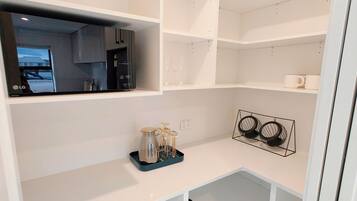 A modern kitchen with white cabinetry, a black coffee maker, and a wine rack.