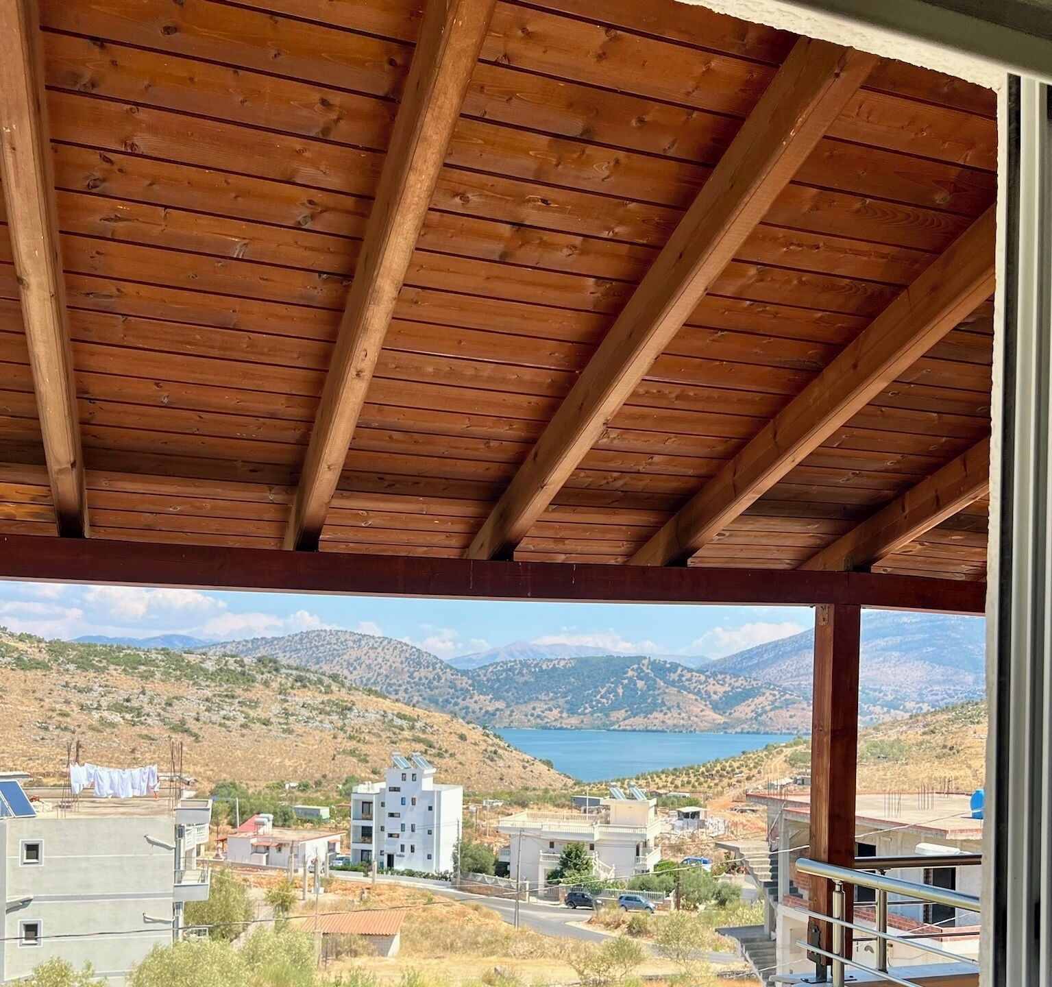 Eine Holzbalkendecke mit Blick auf eine gebirgige Landschaft und einen See.