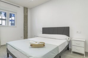 A bedroom with a bed, a bedside table, a window, and a concrete wall. - Apartment 'Ajm' with Wi-Fi and Air Conditioning (Barbate)