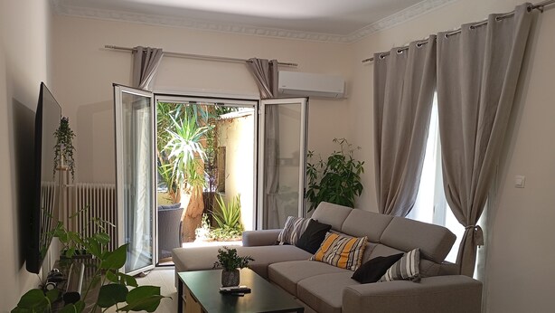 A living room with a sofa, coffee table, and potted plants. - Home & Garden with free parking close to Olympic Stadium (Nea Ionia)