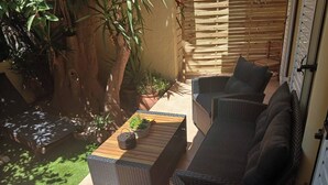 A patio with wicker furniture, a small table with plants, and a wooden fence. - Home & Garden with free parking close to Olympic Stadium (Nea Ionia)