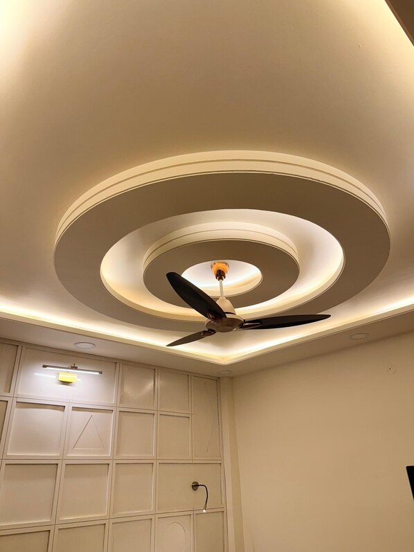 Een plafond met een centraal rond ontwerp, een plafondventilator en inbouwspots.
