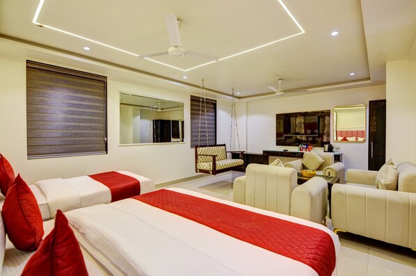 A hotel room with two beds, a sofa, a dining table, and a TV. - Hotel The Krishna (New Delhi)