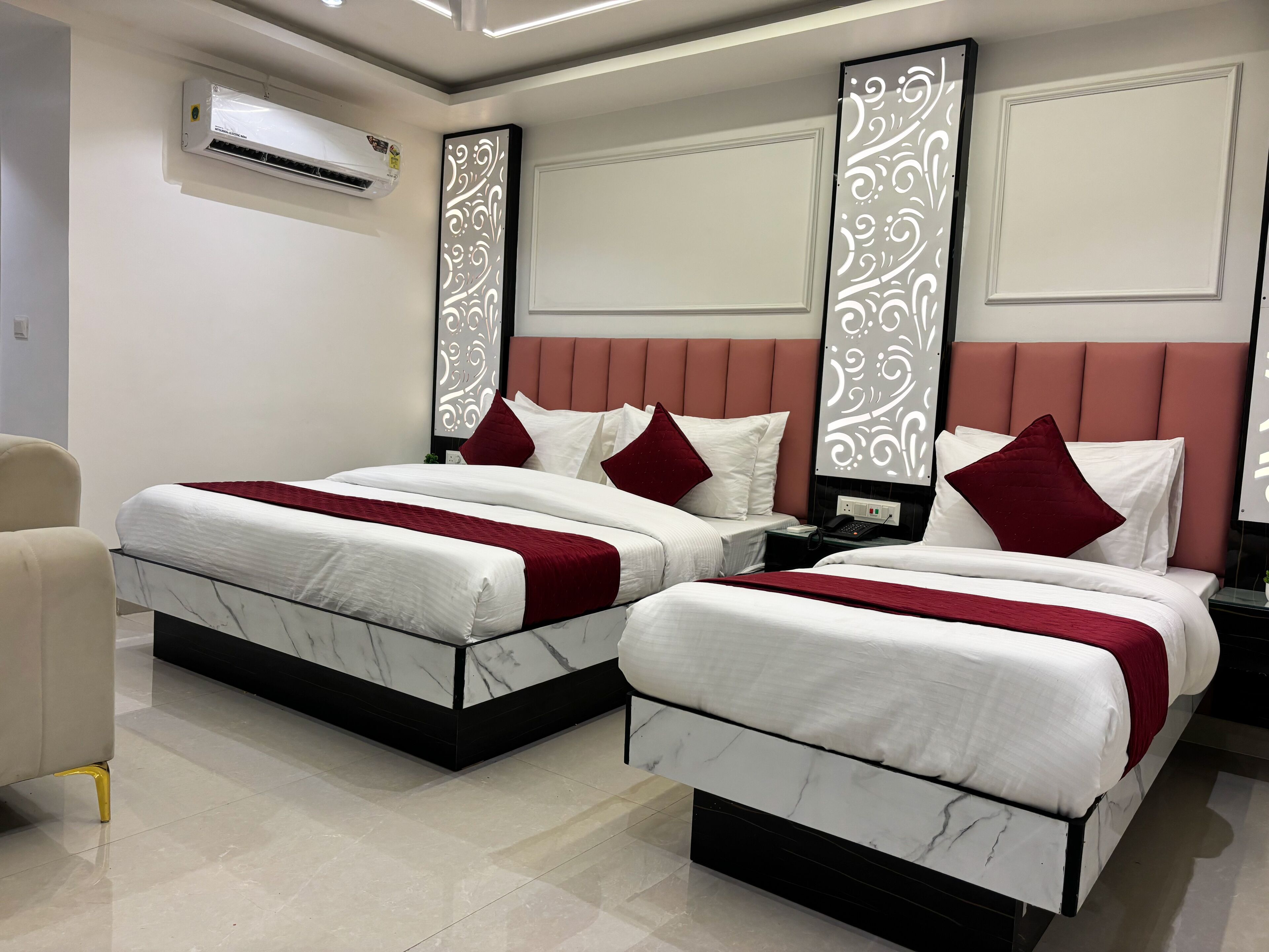 Habitación de hotel con dos camas, una mesita de noche de mármol, teléfono en la mesita y un equipo de aire acondicionado.